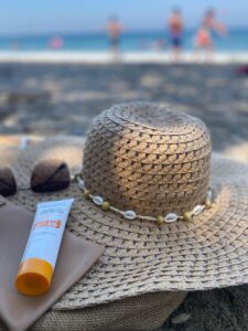 Straw hat and sunscreen laid out on a sandy beach