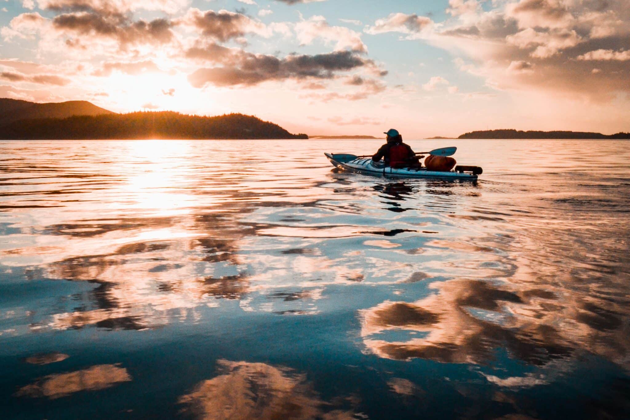 Person kayaking on calm, glassy lake water