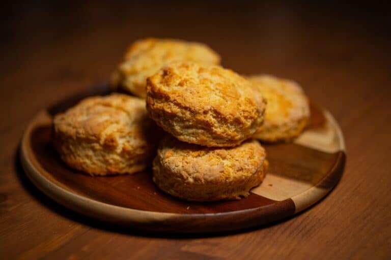 Freshly baked golden buttermilk biscuits on a wooden plate