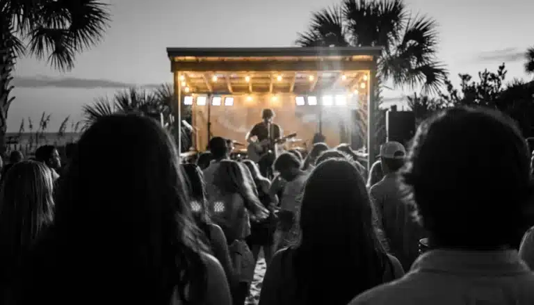 Crowd silhouettes at a beachside stage enjoying live music in Santa Rosa Beach FL at dusk