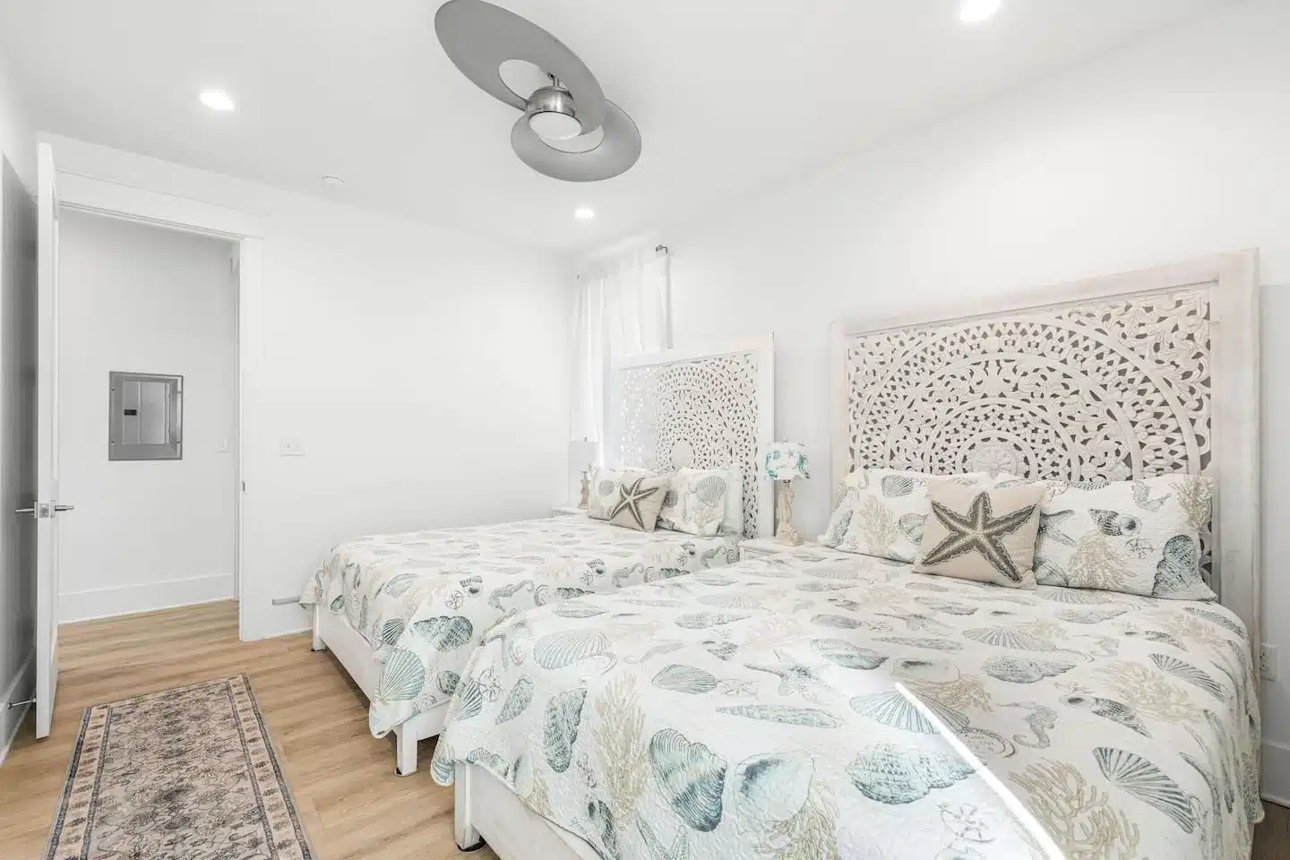 Bedroom with two twin beds, seashell bedding, starfish pillows and carved wooden headboard in a Blue Mountain Beach, FL