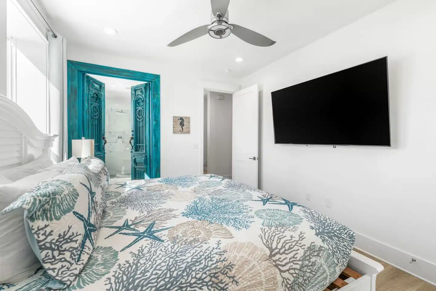 Coastal bedroom with turquoise doors and ocean-themed bedding at Ocean Breeze Santa Rosa Beach, FL