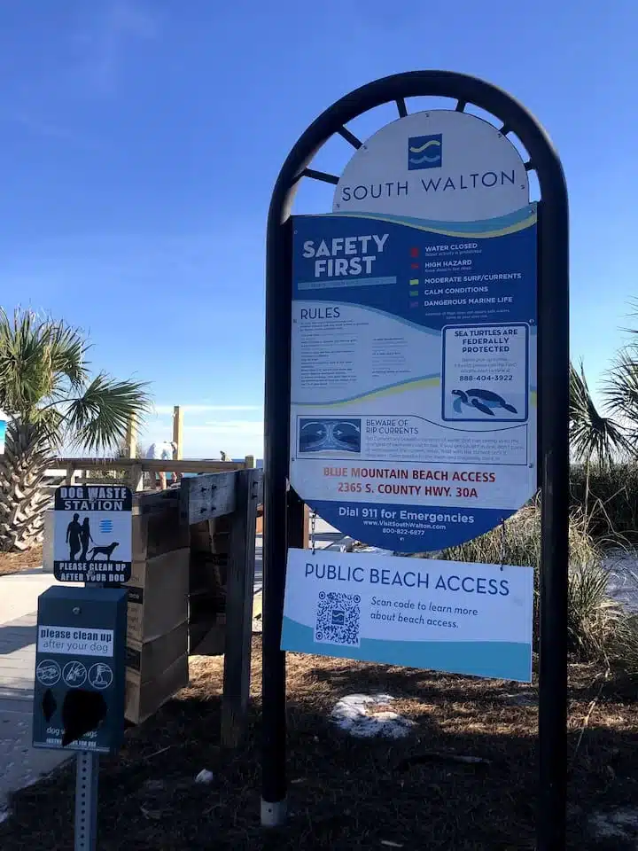 South Walton beach access sign with safety rules near palm trees on Blue Mountain Beach