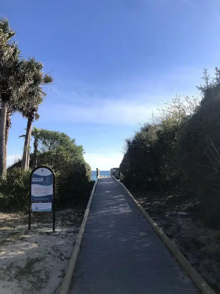 Wooden boardwalk through sand dunes with palms and ocean view at 30A Beach House